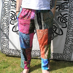 May include: Patchwork pants with a variety of colors and patterns, including pink, blue, green, and orange. The pants are made from different fabrics and are sewn together to create a unique and colorful design.
