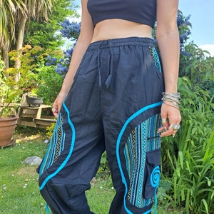 May include: Black pants with blue trim and patterned fabric accents. The pants have a drawstring waist and a relaxed fit.