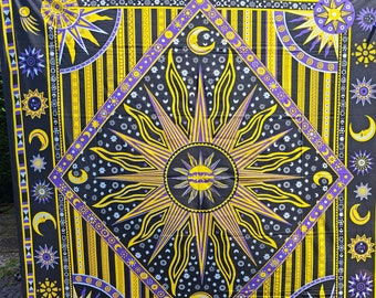 May include: Black tapestry with a celestial design featuring a large sunburst in the center, surrounded by moons, stars, and planets in yellow and purple. The tapestry has a diamond-shaped central design and a border with celestial motifs.