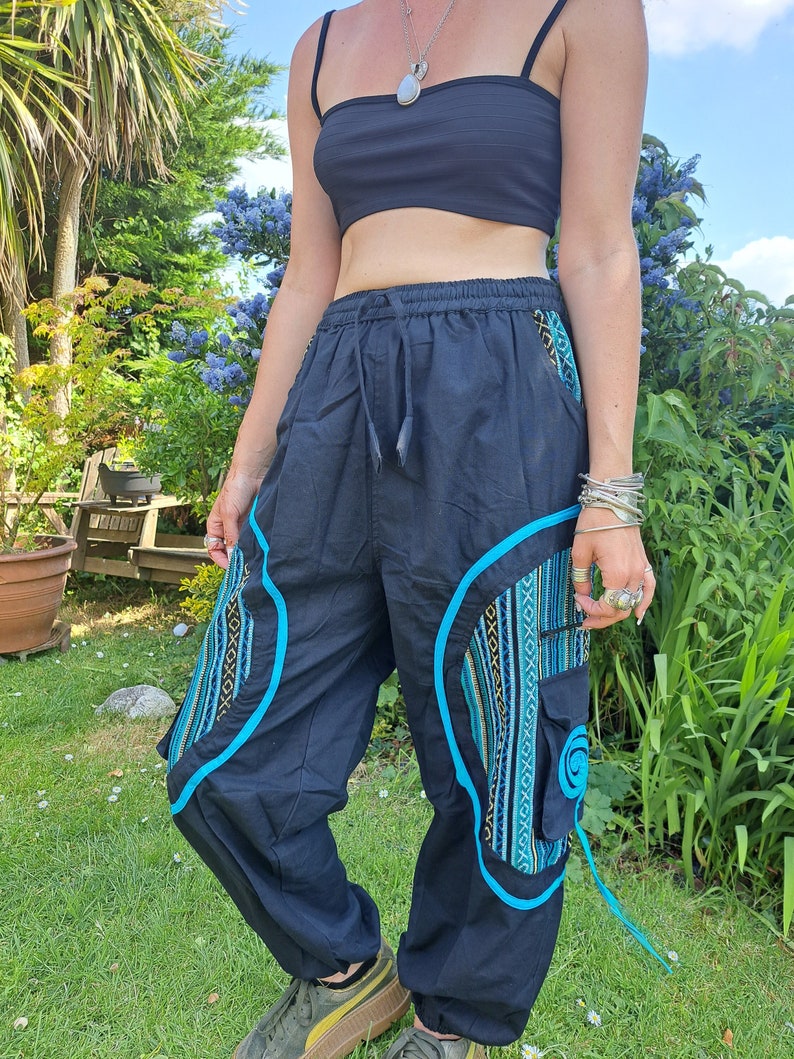 May include: Black pants with blue and yellow patterned details and a blue drawstring. The pants have a loose fit and are made of a soft, comfortable fabric.