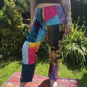 Puede incluir: Pantalones de patchwork con un diseño abstracto y colorido. Los pantalones tienen una cintura con cordón y un corte holgado.