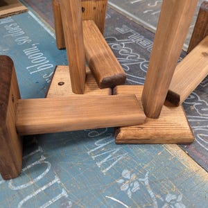 K&ouml;nnte beinhalten: Vier Holz-Regalb&ouml;cke mit einer dunkelbraunen Beize. Die B&ouml;cke sind aus massivem Holz gefertigt und haben ein schlichtes, rustikales Design.