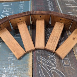 K&ouml;nnte beinhalten: F&uuml;nf Holzregalb&ouml;cke mit einer dunkelbraunen Beize. Die B&ouml;cke sind aus massivem Holz und haben einen rustikalen Look.