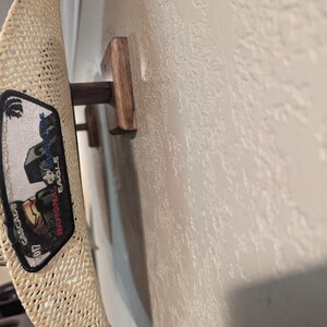K&ouml;nnte beinhalten: Ein Strohhut mit einem Aufn&auml;her mit der Aufschrift "National Eagle Scout Association", der an einem h&ouml;lzernen Huthalter h&auml;ngt.
