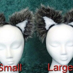 May include: Two sets of furry black and white ears on headbands. The headband on the left is labeled 'Small' and the headband on the right is labeled 'Large'.
