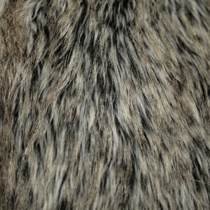 May include: Close-up of a brown and gray faux fur fabric with a black undercoat and a soft, fluffy texture.