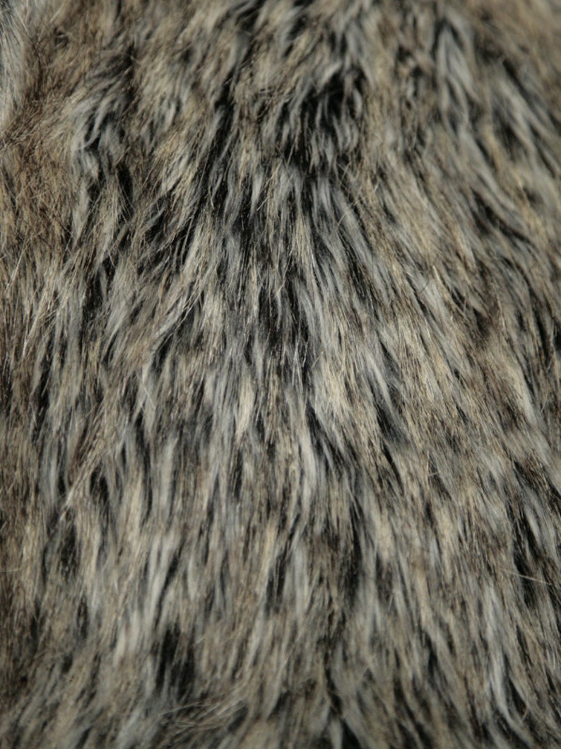 May include: Close-up of a brown and gray faux fur fabric with a black undercoat and a soft, fluffy texture.