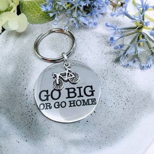 May include: Silver keychain with a round metal tag that says "Go Big or Go Home" with a small silver bicycle charm attached.
