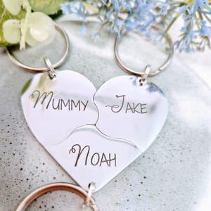 May include: Three silver heart-shaped keychains with the names "Mummy", "Jake", and "Noah" engraved on them.