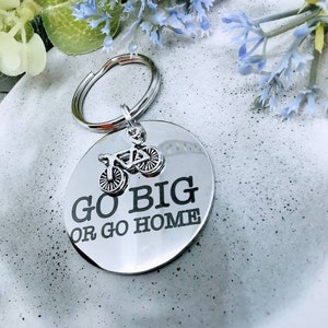 May include: Silver keychain with a round tag that says "Go Big or Go Home" with a small bicycle charm attached.
