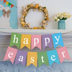 May include: A colorful banner with the words "happy easter" hanging on a white mantel. The banner is made of fabric and has a rustic look. There is a wreath with yellow eggs and a vase of white flowers on the mantel.