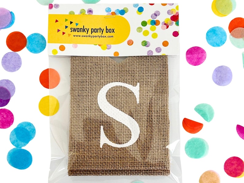 May include: A burlap banner with the letter "S" printed in white. The banner is packaged in a clear plastic bag with a colorful confetti design.