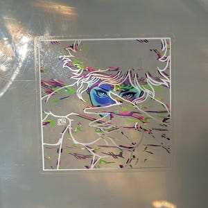 May include: A sticker featuring an illustration of a person with blue eyes and white hair. The artwork has colorful accents of pink, green, and purple. The artist's initials, CYN, are in the lower left corner.