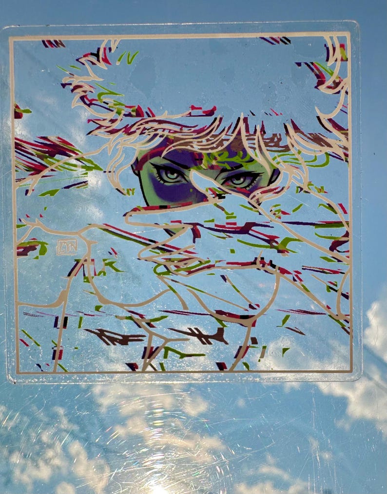 May include: Square sticker with an illustration of a person's face with green eyes and purple skin. The artwork has a blue background with white, red, and green abstract lines. The sticker is in a clear plastic case.