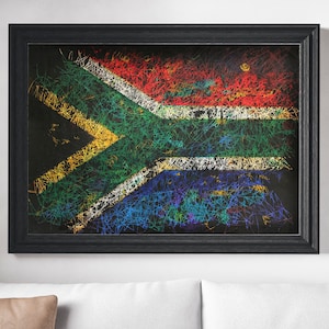 May include: A framed artwork featuring the South African flag, rendered with colorful, scribbled lines on a black background. The flag's design includes red, white, blue, green, and yellow elements. The frame is black.