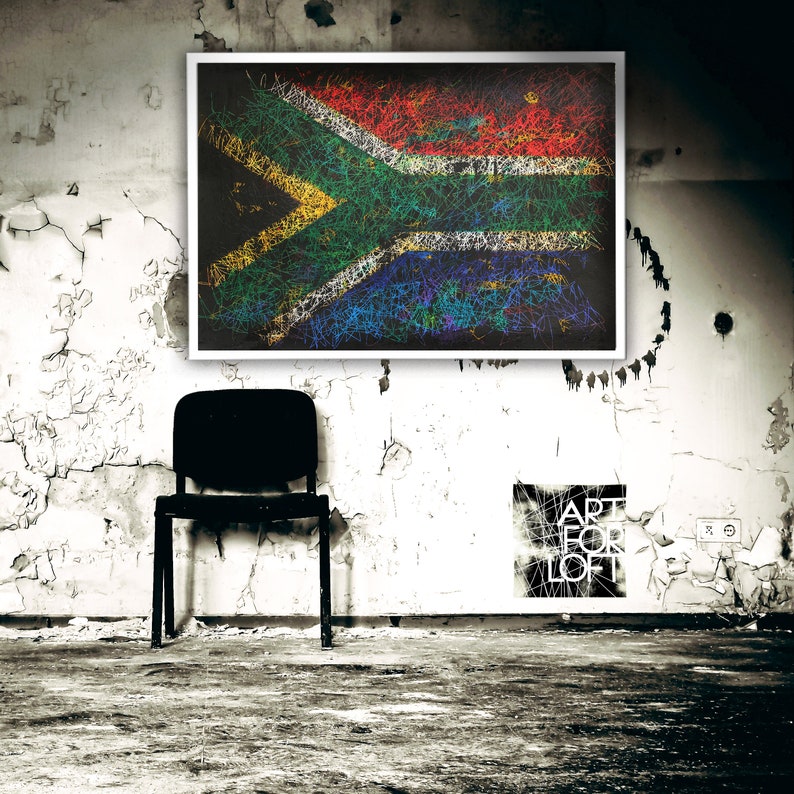 May include: A framed artwork featuring the South African flag rendered in a colorful, scribbled style. The artwork hangs on a distressed white wall, with a black chair in front. The words "ART FOR LOFT" are visible on a poster.
