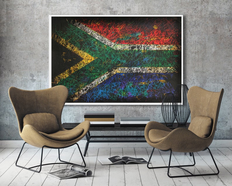 May include: A framed artwork depicting the South African flag, rendered with colorful, scribbled lines. The artwork hangs above a dark console table, flanked by two brown armchairs with black metal frames. A modern living room setting.