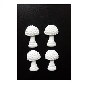 May include: Four white ceramic mushroom-shaped ornaments with a textured surface. The ornaments are arranged in two rows of two.