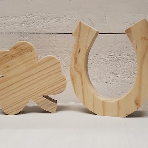 May include: Two wooden craft blanks, one shaped like a four-leaf clover and the other shaped like a horseshoe.