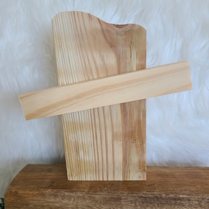 May include: Two pieces of unfinished wood, one standing upright and the other lying horizontally across the top. The wood is light brown and has a natural grain.