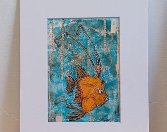 May include: A mixed media painting of an orange fish with long, thin, blue antennae. The fish is swimming in a turquoise blue background with a textured, layered look. The painting is framed in a white mat.