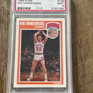 May include: A 1989 Fleer Kiki Vandeweghe basketball card, graded PSA 9 Mint. The card features a photo of Vandeweghe in his New York Knicks uniform, holding a basketball. The card is encased in a clear protective holder.