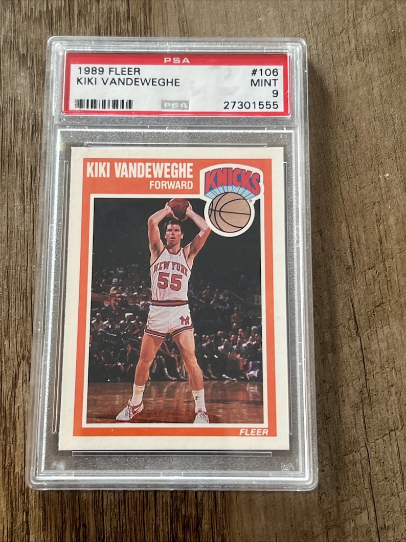 May include: A 1989 Fleer Kiki Vandeweghe basketball card, graded PSA 9 Mint. The card features a photo of Vandeweghe in his New York Knicks uniform, holding a basketball. The card is encased in a clear protective holder.