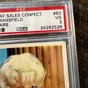 May include: A vintage trading card featuring a woman with blonde hair and a white dress. The card is graded by PSA and has a grade of VG 3. The card number is #63. The text on the card reads "AF SALES CONFECT. MANSFIELD ARS".