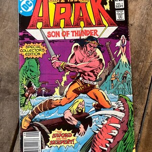 May include: A comic book cover featuring a muscular, red-skinned man with a sword, fighting a large, green serpent. The cover is titled "Arak, Son of Thunder" and features the text "Big 1st Issue!" and "The Sword and the Serpent!"