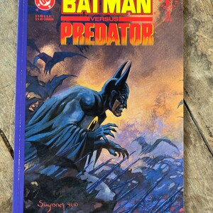 以下が含まれることがあります： 「Batman Versus Predator」と題されたヴィンテージコミック。表紙には、ドラマチックでカラフルな背景を背景に、ダークブルーのコスチュームを着たバットマンが描かれています。DCコミックスのロゴと、太字の黄色と赤の文字でタイトルが表示されています。