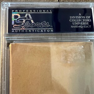 May include: A black and silver Professional Sports Authenticator (PSA) grading label with the text "A Division of Collectors Universe, NASDAQ: CLCT".