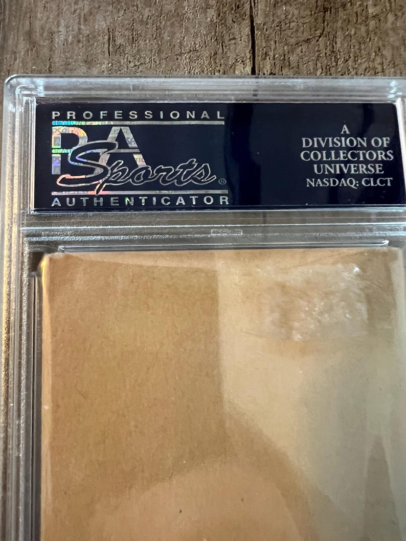 May include: A black and silver Professional Sports Authenticator (PSA) grading label with the text "A Division of Collectors Universe, NASDAQ: CLCT".