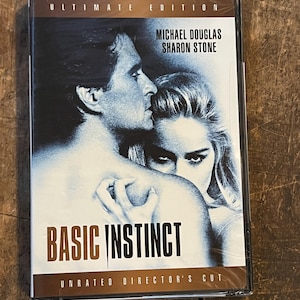 May include: DVD of the movie "Basic Instinct" featuring Michael Douglas and Sharon Stone. The cover art shows a close-up of the actors in a dramatic pose. The DVD case is sealed in plastic and labeled "Ultimate Edition".