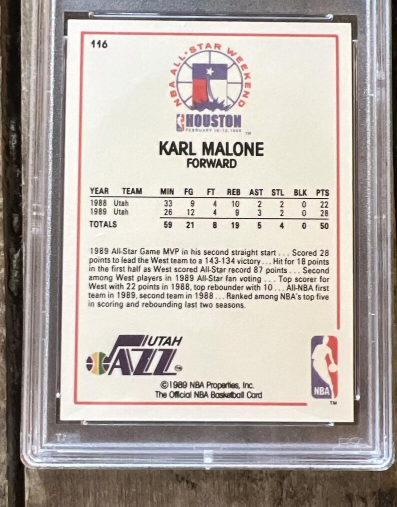 Pu&ograve; includere: Una carta di basket NBA del 1989 con Karl Malone, ala piccola degli Utah Jazz. La carta &egrave; bianca con accenti rossi, blu e neri. La carta presenta una foto di Malone con la sua divisa degli Utah Jazz, insieme alle sue statistiche e una descrizione dei suoi risultati.