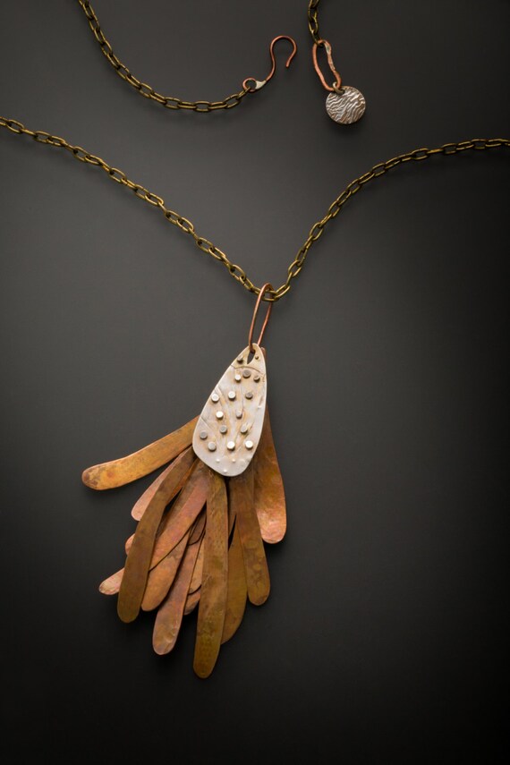 A collection of moveable parts make up this large copper pendant. It hangs sturdily from an antique brass clock chain.
