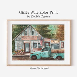 May include: A watercolour print featuring a rustic building labelled Cleary's General Store and Annie's Diner with a vintage teal pickup truck parked in front. The scene includes an American flag, various signs, and colourful flowers in a wooden frame.