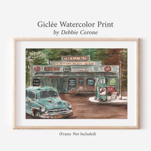 May include: A giclée watercolor print by Debbie Cerone depicting a vintage teal car parked in front of Chuck's Custom Body Shop. The scene includes a weathered building with various signs, a retro gas pump, and surrounding trees in a rustic setting.