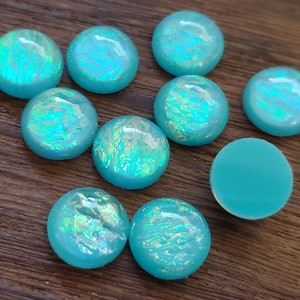 May include: A collection of ten turquoise cabochons with iridescent shimmer. The cabochons are round and have a smooth, polished surface.
