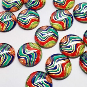 May include: A collection of colorful, round cabochons with a swirling pattern of red, green, blue, and gold. The cabochons are arranged on a white surface, showcasing their vibrant design. These decorative elements could be used for jewelry making or other craft projects.