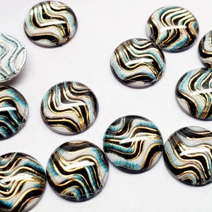 May include: Assortment of round, black, white, and gold cabochons with a wavy pattern. The cabochons are approximately 1 inch in diameter.