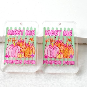 May include: Two rectangular clear acrylic pendants featuring a light green vertical striped background. The design includes pink and orange pumpkins with polka dot patterns, small stars, and the pink text "MEET ME at the PUMPKIN PATCH".