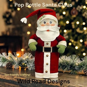 Op de afbeelding: Een kerstmanfiguur gemaakt van een gerecyclede fles, met een rode muts met witte pompon, een witte baard, groene wanten en een zwarte riem met een gouden gesp. De tekst Pop Bottle Santa Claus en Wild Road Designs is zichtbaar.