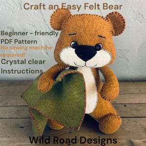 Könnte beinhalten: Ein brauner Filzbär als Plüschtier, der ein grünes Filzstück mit roten Nähten hält. Der Text lautet: Craft an Easy Felt Bear, Beginner-friendly PDF Pattern, No sewing machine required!, Crystal clear Instructions, Wild Road Designs.