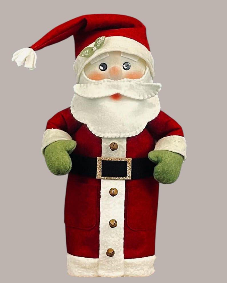Pu&ograve; includere: Una statuetta di Babbo Natale in peluche con un cappello rosso con pompon bianco, un cappotto rosso con bordo bianco, muffole verdi e una cintura nera con fibbia dorata. Il cappotto presenta una striscia bianca verticale con quattro campanellini.