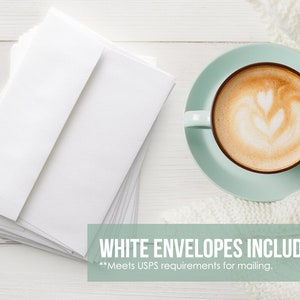 Może przedstawiać: Stosik białych kopert na białym drewnianym blacie. Filiżanka kawy z latte art stoi na spodku obok białego dzianego koca. Na zdjęciu widnieje tekst "WHITE ENVELOPES INCLUDED" wraz z dopiskiem "**Meets USPS requirements for mailing."