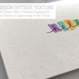 May include: A close-up of a white card with a textured surface. The card has the text "SUPERIOR OUTSIDE TEXTURE" and "Visible Fibers Offer a Striking Appearance" and "Gentle Texture is Captivating to the Touch" printed on it. The word "hello" is written in colorful marker across the top of the card.
