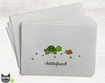 Op de afbeelding: Een stapel blanco wenskaarten met een illustratie van een groene schildpad en een slak en de tekst "hello friend".