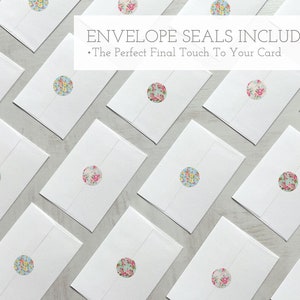 May include: White envelopes with floral patterned round stickers. The text "Envelope Seals Included" and "The Perfect Final Touch To Your Card" is displayed above the envelopes.
