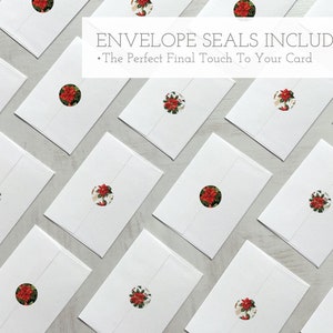 K&ouml;nnte beinhalten: Wei&szlig;e Umschl&auml;ge mit roten und gr&uuml;nen floralen Aufklebern. Der Text "Envelope Seals Included" und "The Perfect Final Touch To Your Card" ist &uuml;ber den Umschl&auml;gen gedruckt.