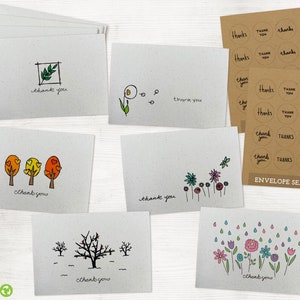 May include: Set of 5 thank you cards with different illustrations. The cards are printed on recycled paper and feature hand-drawn designs of a branch, a dandelion, trees, flowers, and raindrops. The cards are accompanied by 12 round envelope seals with the text "thank you" or "thanks" in various fonts and styles.
